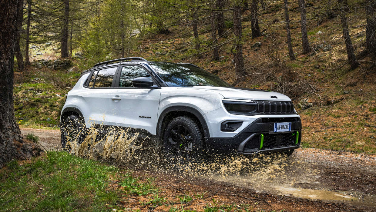 Jeep Avenger 4xe Hybrid білого кольору їде через калюжу у лісі