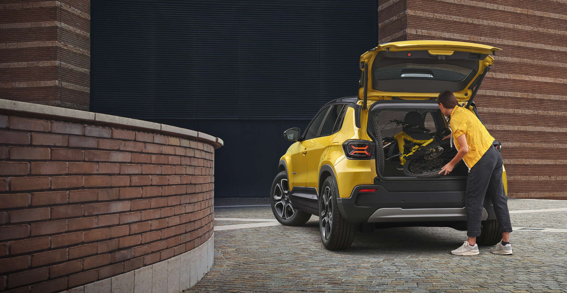 Jeep Avenger, дівчина кладе речі у відчинений багажник